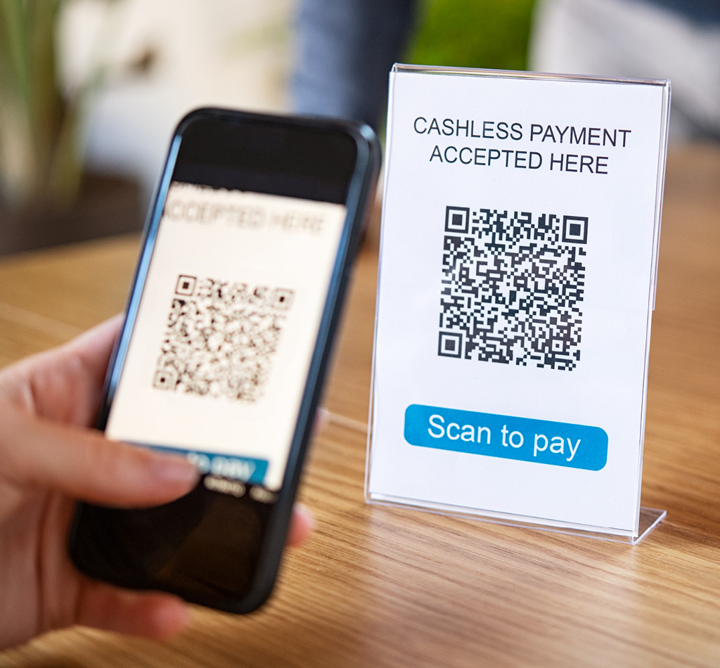 Customer scanning QR code in coffee shop to make a cashless payment online.