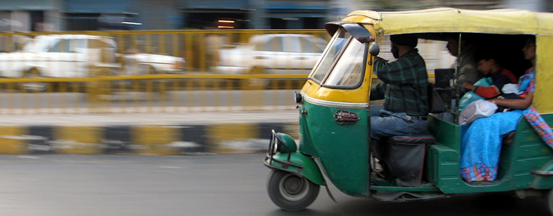 Un pousse-pousse vert et jaune à moteur parcourt les rues de Delhi, en Inde