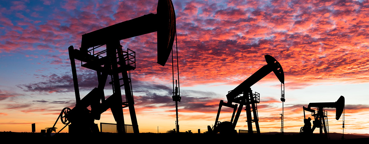 Oil pumpjacks in silhouette at sunset.