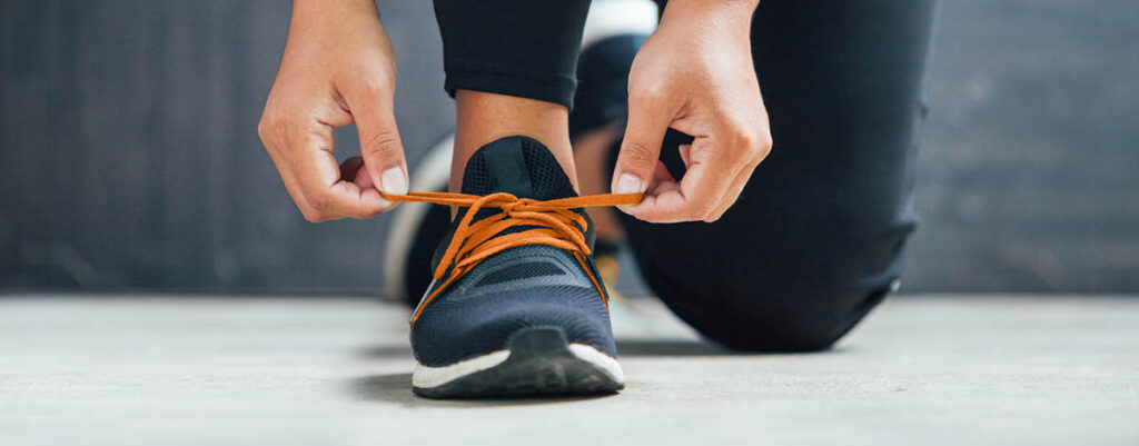 Woman tying her running shoes preparing for a run.