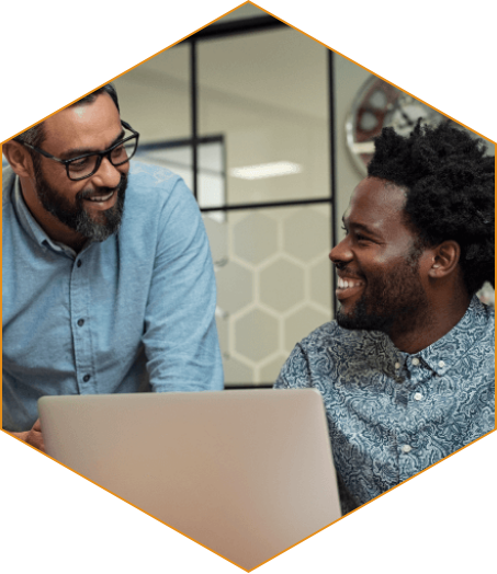 Two BIPOC men talking in front of a laptop.