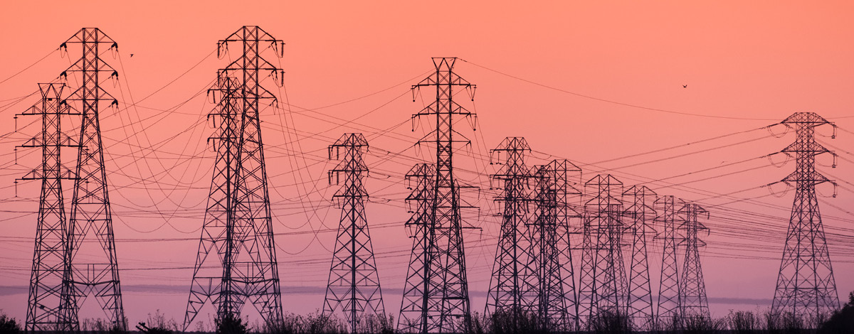 Sunset view of high voltage electricity towers on the shoreline of San Francisco bay area; California.