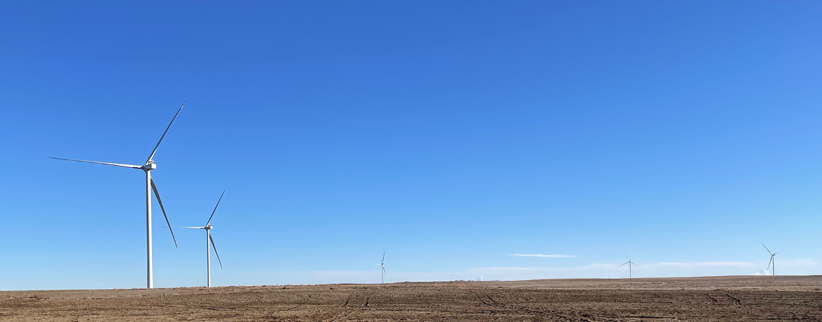 Image of multiple wind turbines against the horizon