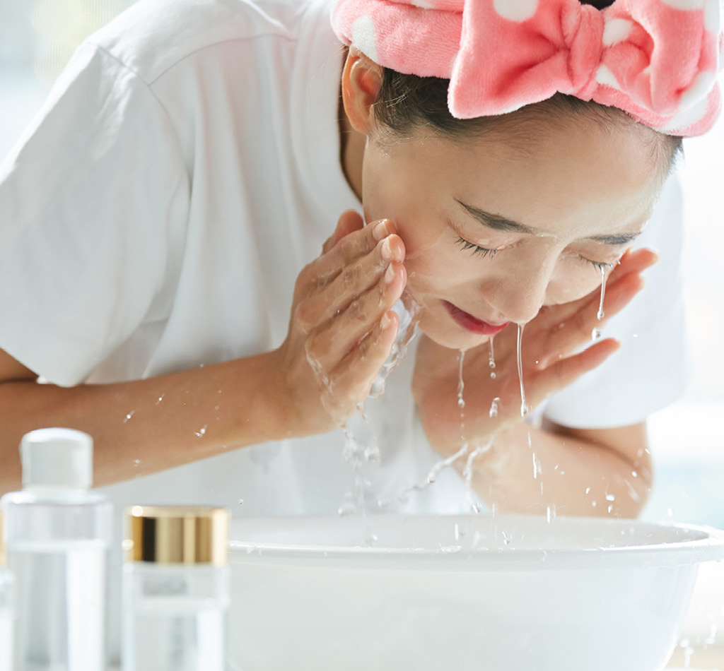 Young Asian woman washing her face using skincare products.