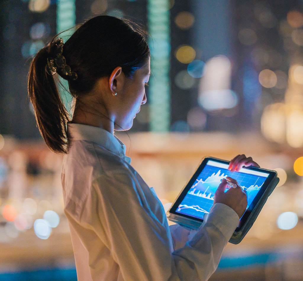 Asian lady using a tablet to review stock exchange financial and investment data.