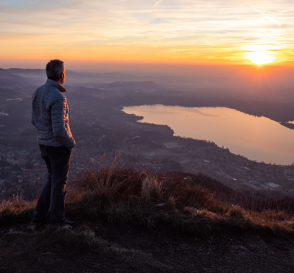 Hiker looking off at the sun over the horizon.