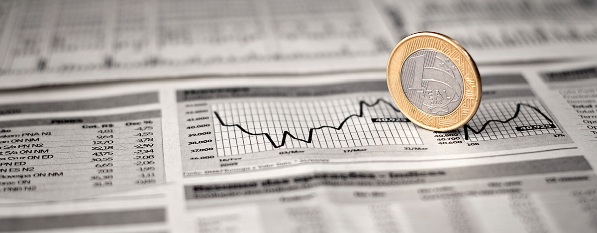 Brazilian economy, a 1 Real coin over a line chart graphic in a newspaper.