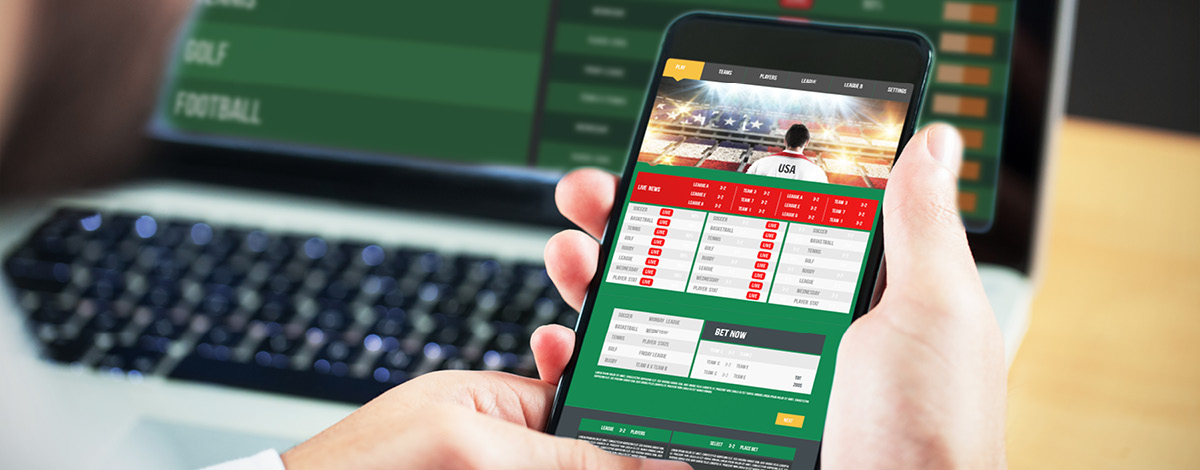 Using smartphone & laptop to view gambling app.