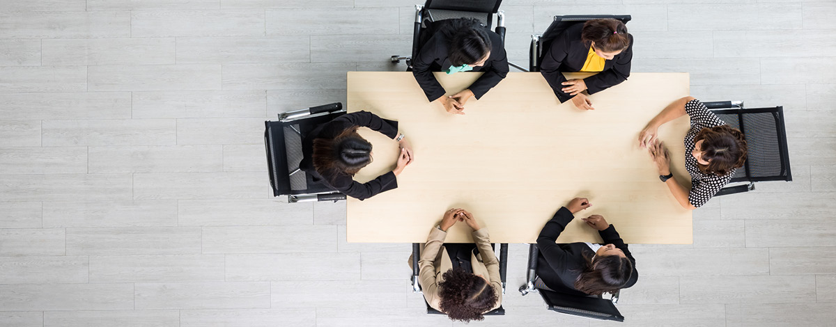 Top-down view of a meeting with 6 people sitting at a table.