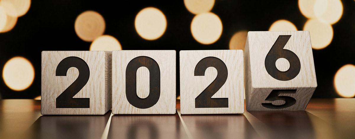 Wooden number blocks changing from 2025 to 2026 on a table against a golden bokeh background.