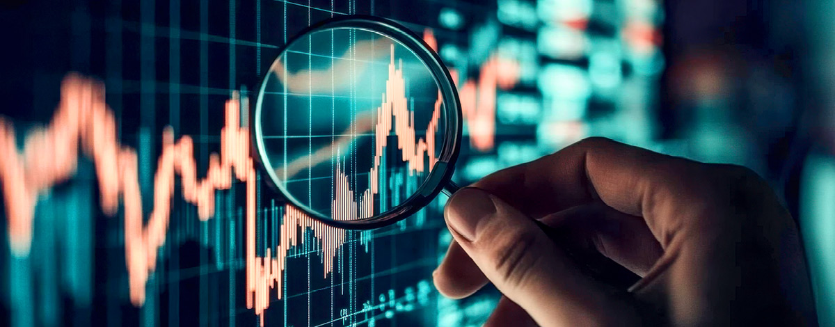 Hand holding a magnifying glass over a stock market chart.