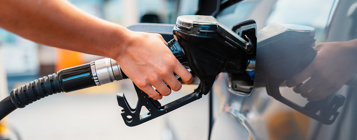 Closeup of a person pumping gasoline fuel in their car at gas station.