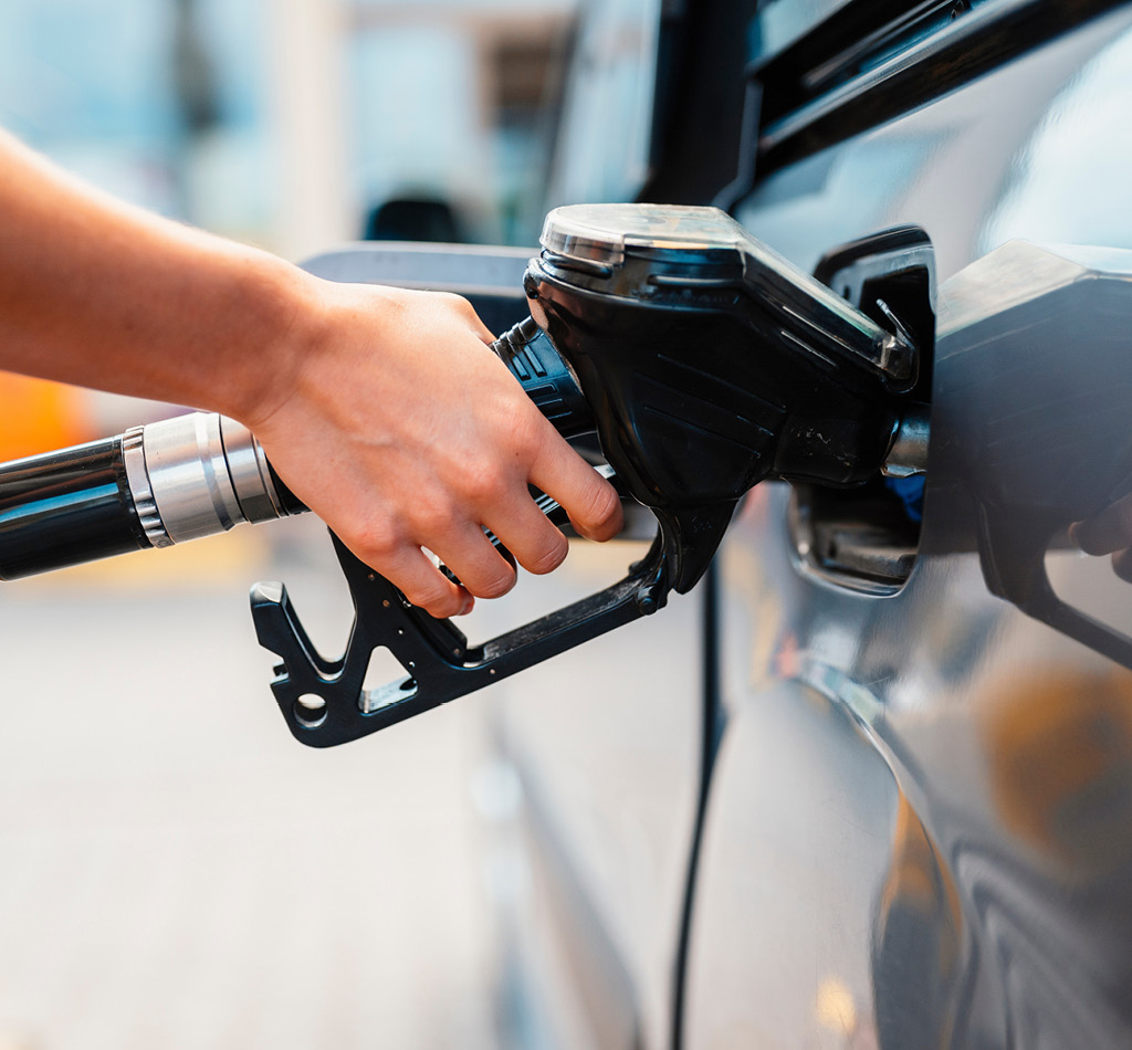 Closeup of a person pumping gasoline fuel in their car at gas station.