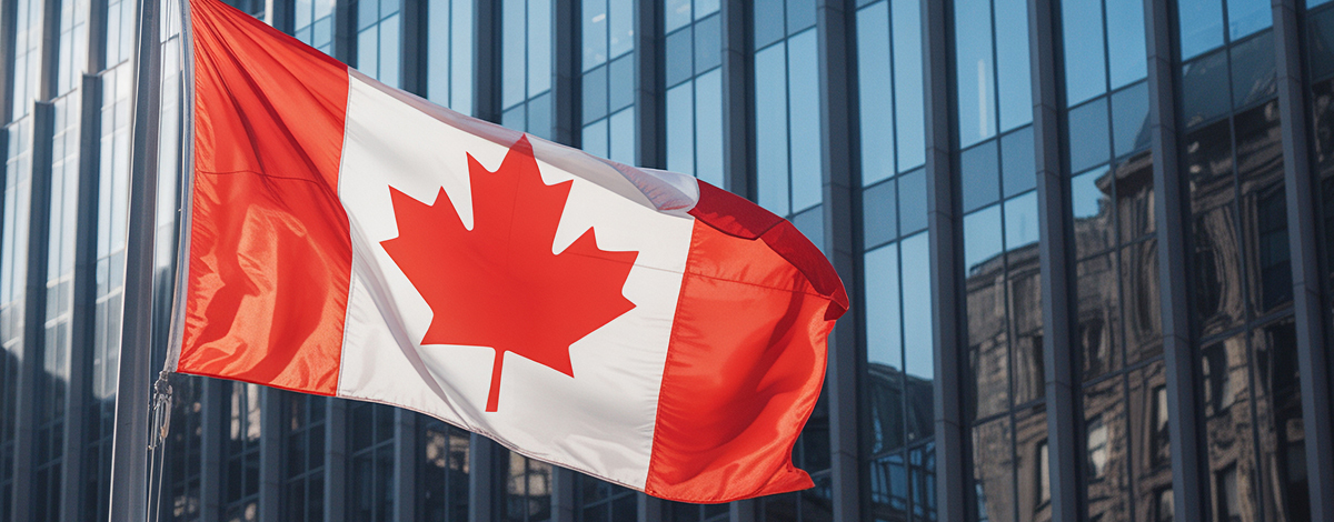 Image du drapeau canadien flottant au vent devant un immeuble de bureaux.