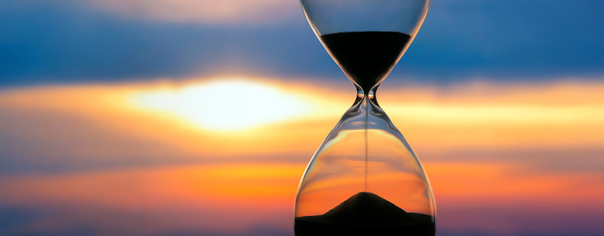 Hourglass on the background of a sunset. The value of time in life. An eternity…