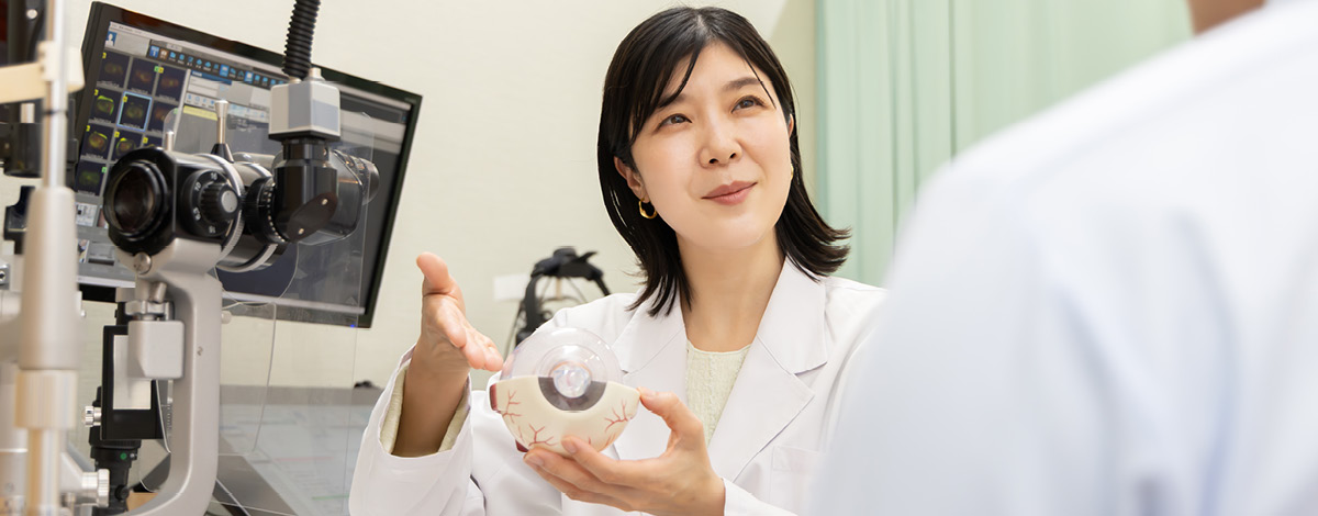 An ophthalmologist explains the examination while holding an eyeball model.